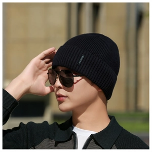 Detailed close-up of a black ribbed knit beanie featuring a small logo label on the cuff