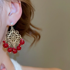 Close-up of vintage flower drop earrings with red beads and zircon on model ear