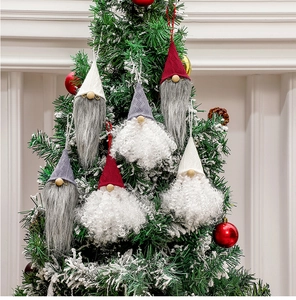 Close-up of assorted Swedish gnome ornaments hanging on a snowy Christmas tree branch