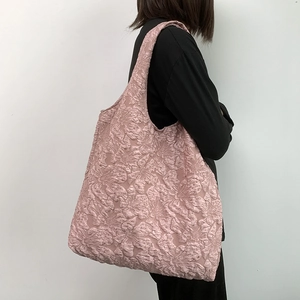 Detail of pink floral jacquard texture on a minimalist tote bag worn by a model