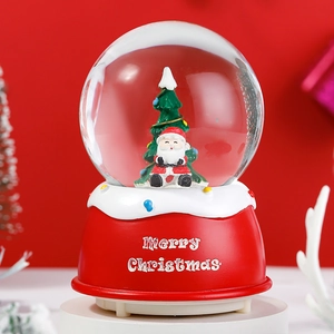 Close-up of Santa Claus and Christmas tree inside a festive red base snow globe