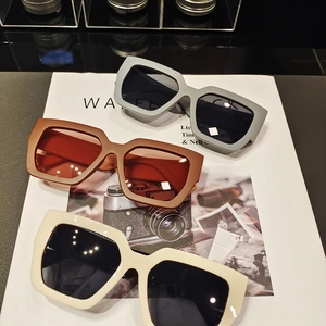 Detailed stack of large square matte sunglasses in grey, brown and beige colors