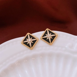 Macro view of 16K gold-plated rhombus stud earrings with black inlay and star detail