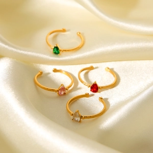Macro detail of hammered gold rings with pear-cut emerald and ruby zircon stones