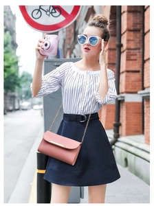 Pink chain crossbody bag paired with red striped top and navy high-waisted skirt