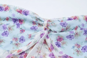 Detailed macro view of the front knot design on a sheer blue floral mesh dress