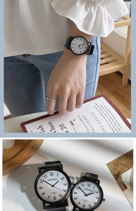 Detailed view of black quartz watch with white dial on wrist and wood decor