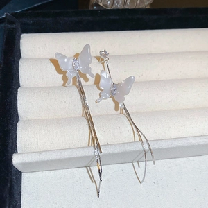Detail of silver needle earrings featuring resin butterfly wings and long tassel chains