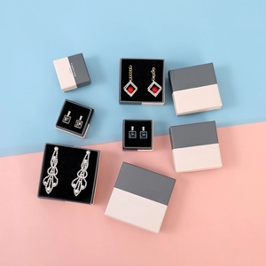 Elegant jewelry boxes set with earrings and necklaces on a blue and pink background