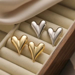 Pendientes de corazón minimalistas bañados en oro y plata en un joyero de madera