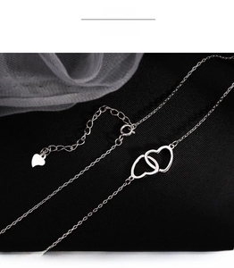 Macro detail of interlocking double hearts necklace in silver with adjustable chain