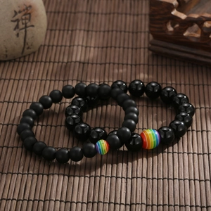 Dettaglio macro di perle in pietra vulcanica nera con accento arcobaleno su stuoia di bambù