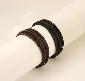 Detail of multi-layer woven leather bracelets in black and brown on a white display