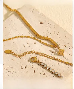 Détail d'un ensemble de bracelets dorés avec pendentif géométrique et chaîne de tennis zircon