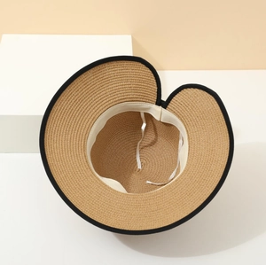 Close-up of woven straw hat featuring black fabric trim and split rear ponytail opening