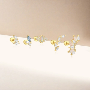 Macro detail of five gold S925 sterling silver cartilage studs with opal and marquise zircon