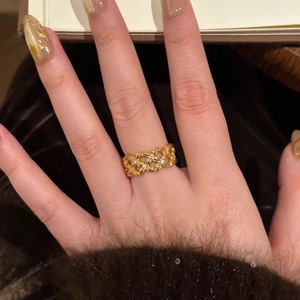 Gold plated hollow crisscross ring with zircon pavé worn on finger in a cozy setting
