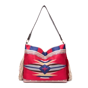 Detail of red woven bohemian tote bag featuring geometric patterns and ivory fringes