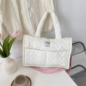 Borsa trapuntata bianca con motivo a nuvola e tracolla rosa in un ambiente lifestyle curato