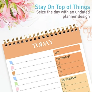 Detailed close-up of a pink spiral undated daily planner with task priority sections