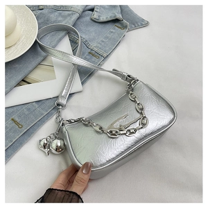 Macro detail of silver metallic shoulder bag with crinkled texture and chunky chain