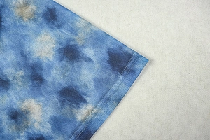 Macro shot of blue and white tie-dye knit fabric with durable double-needle stitching