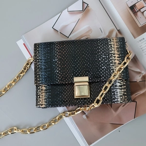 Macro shot of faux snake skin texture and gold chain strap on stylish shoulder bag