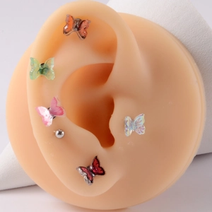 Detailed view of colorful butterfly stud earrings worn on a silicone model ear