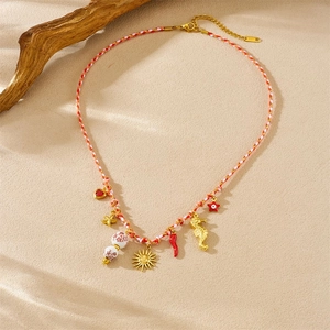 Detailed flat lay of ocean theme necklace with starfish and seahorse on sand background