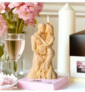 Detail of lit couple-shaped scented candle with rose relief on romantic pink base