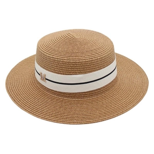 Close-up of brown straw bucket hat featuring white ribbon with a golden metal M logo
