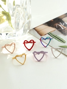 Close-up of six minimalist heart-shaped rings in gold, silver, and vibrant color finishes