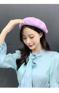 Detail of a purple wool beret and blue satin blouse with a delicate bow neckline tie