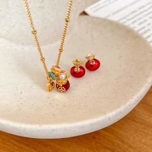 Detail view of gold-plated lucky bag jewelry set with red stones and pearls on ceramic plate