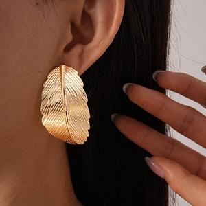 Detail showing high-shine metallic leaf earrings with realistic vein textures on a model