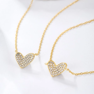 Detail of two gold plated stainless steel heart necklaces with micro inlaid zircons