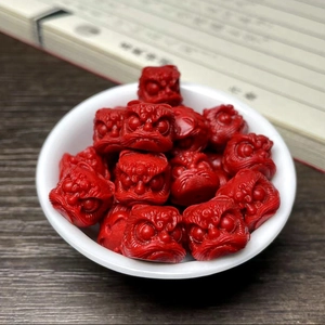 Close-up of red lion-head shaped vegetable ivory beads in a white bowl for DIY jewelry
