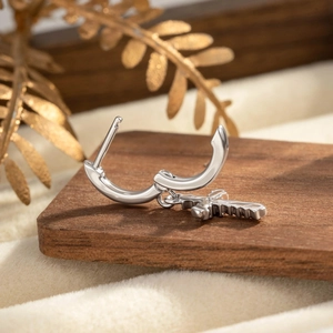 Boucle d'oreille croix en argent minimaliste sur socle en bois avec un éclairage élégant