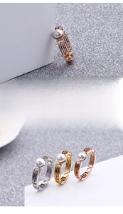 Detail view of gold and silver hollow geometric rings featuring white pearls and fine plating