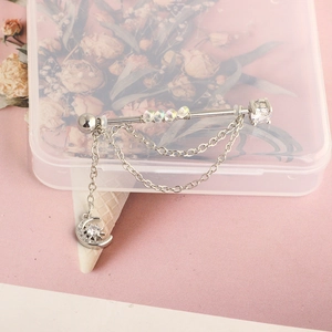 Detail of industrial piercing bar with clear beads, chains and moon star pendant