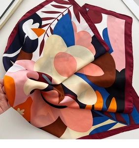 Detailed view of hand-held floral silk scarf with vibrant colorful artistic patterns
