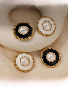 Macro detail of vintage gold braided earrings with pearl center and enamel inlay