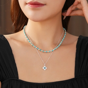 Detail of layered turquoise beaded necklace with a sparkling floral zircon pendant