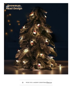 Detail of warm white LED snowman fairy lights with scarves on a snow-covered Christmas tree
