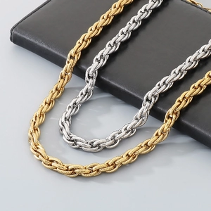 Close-up of gold and silver hammered Cuban link chains on a dark leather surface