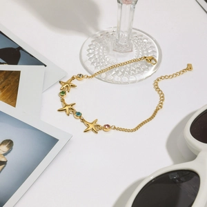 Close-up of golden starfish bracelet with colorful crystals in a summer vacation scene