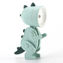 Dettaglio mini lampada LED a forma di dinosauro verde con testina rotonda su sfondo bianco