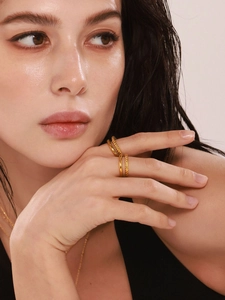 Close-up of a double-layered gold twisted open ring set worn by a female model