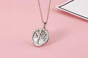Detail of silver tree of life pendant with white mother of pearl inlay on pink background