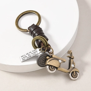 Retro bronze scooter keychain with leather wrap and engraved quote on white platform